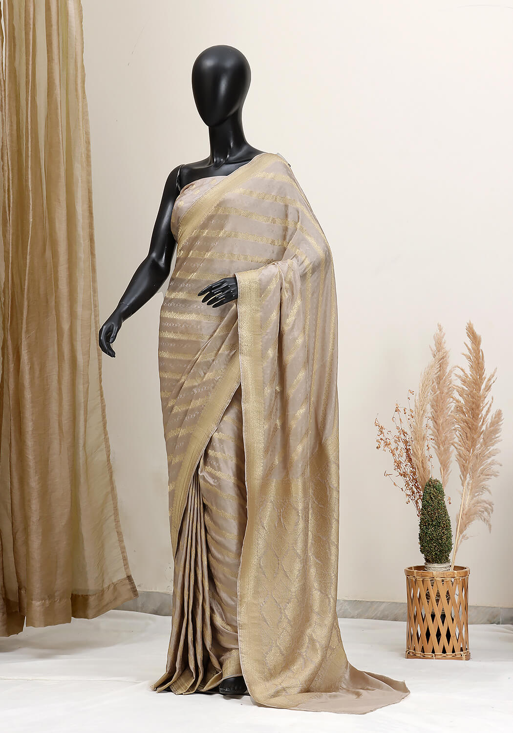 Mannequin wearing a beige saree with a neutral background